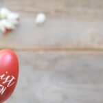 Easter Decor - a hand holding a red painted egg with the words cherry is risen written on it