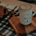 Seasonal Scents - a cup of coffee sitting on top of a wooden cutting board