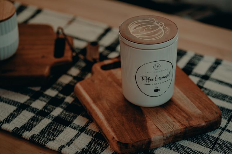 Seasonal Scents - a cup of coffee sitting on top of a wooden cutting board