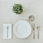 Table Setting - white ceramic plate beside stainless steel fork and bread knife on white table