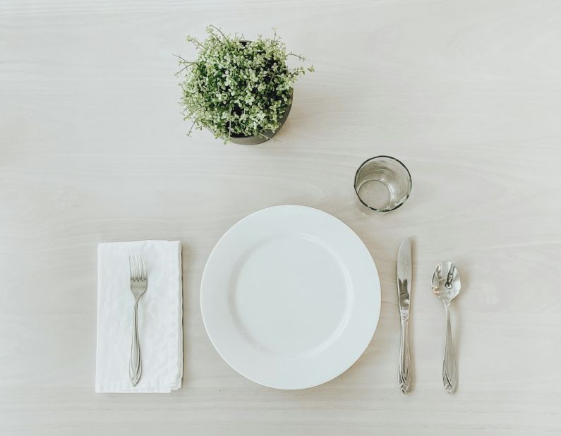 Table Setting - white ceramic plate beside stainless steel fork and bread knife on white table